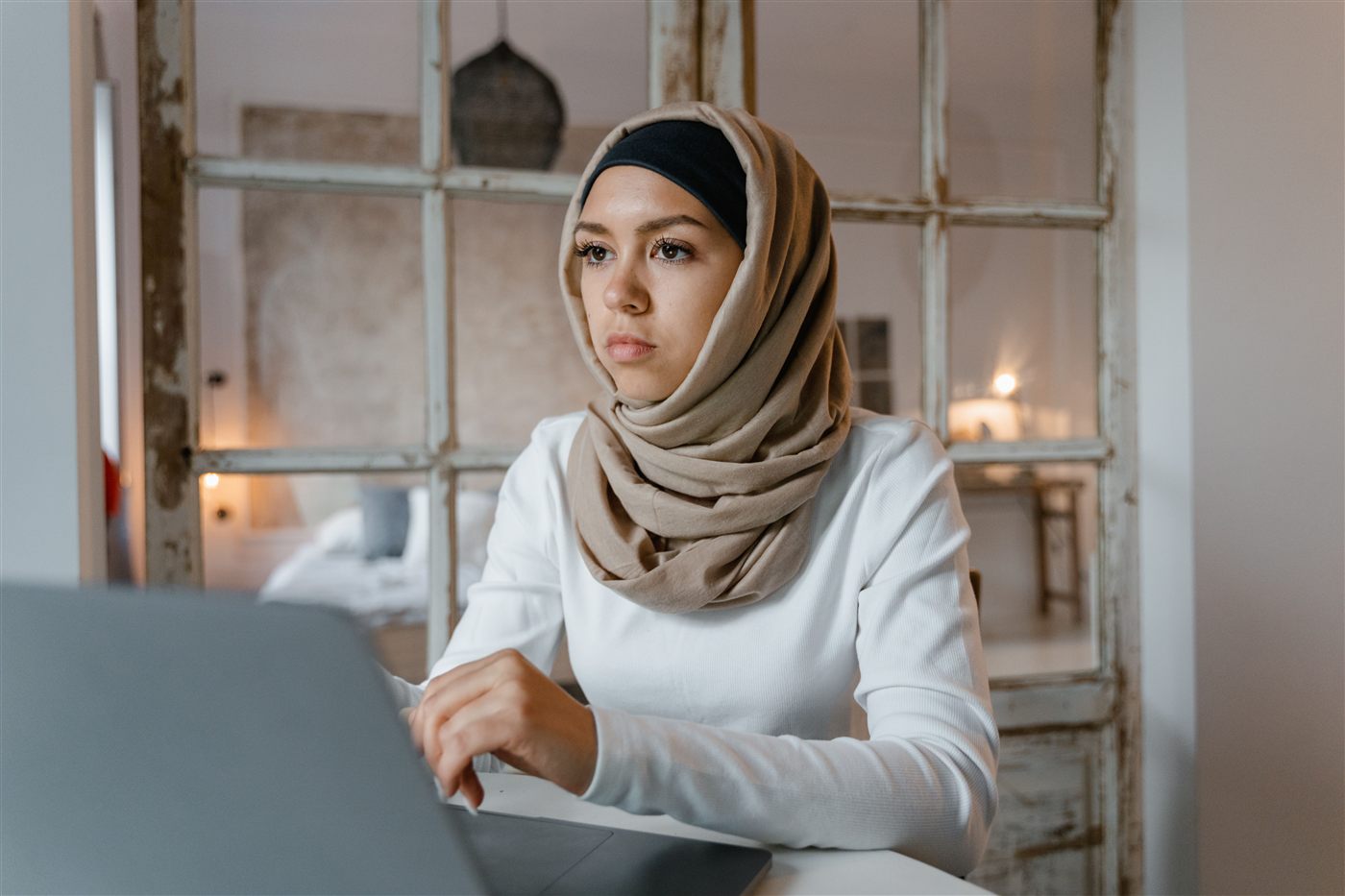 Muslim woman in hijab attending a live online Quran class on her laptop